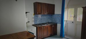 a small kitchen with wooden cabinets and blue tiles at Piccolo Tirreno Hotel Residence in Procida +37 photos
