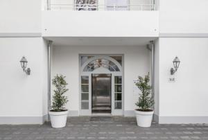 a white building with two potted plants in front of a door at Kleine Lagune in Zingst