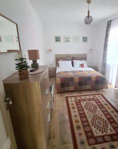 a bedroom with a bed and a dresser with a lamp at Apartament Eminescu 2 in Zărneşti