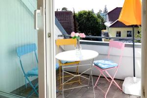 een tafel en stoelen op een balkon met een vaas met bloemen bij Kranichflug in Zingst