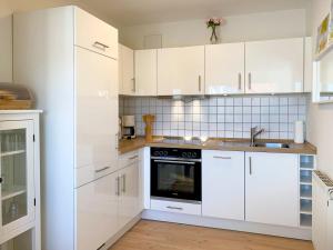 een keuken met witte kasten, een wastafel en een fornuis bij Kranichflug in Zingst