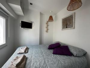 um quarto com uma cama com almofadas roxas e uma televisão em Just Sezimbra em Sesimbra