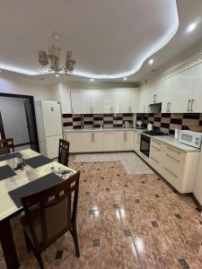 a large kitchen with white cabinets and a table and chairs at Dendrarium Park Apartament in Chişinău