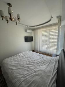a bedroom with a white bed and a window at Dendrarium Park Apartament in Chişinău
