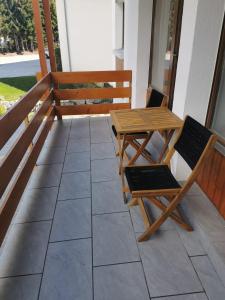 un tavolo e sedie in legno su una veranda con panchina di Charmant appartement balcon et parking a Lens