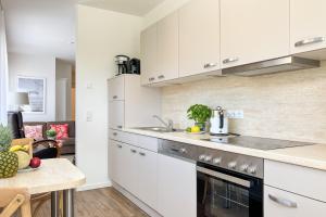 a kitchen with white cabinets and a counter top at Meerquartier, Whg 01 in Neuhaus