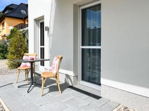 dwa krzesła i stół na patio z oknem w obiekcie Meerquartier, Whg 01 w mieście Neuhaus