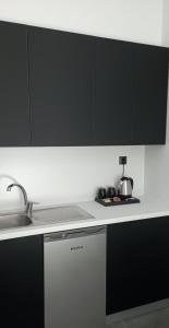 una cocina con armarios en blanco y negro y fregadero en Studio Eleni en Plomari