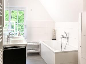 een witte badkamer met een bad en een wastafel bij ParkLiebe Apartment 6 in Wustrow