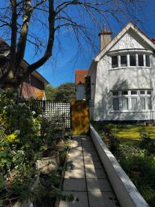 a white house with a fence and a sidewalk at A gem close to Canford Cliff and Sandbanks beach in Parkstone