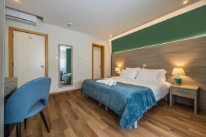 a bedroom with a large bed and a blue chair at The Howard Hotel in Sliema