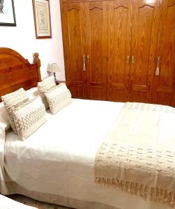 een slaapkamer met een groot wit bed en houten kasten bij Casa Ana in Vejer de la Frontera