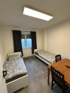 a room with two beds and a table and a window at Schöne Apartments im Zentrum von Bottrop BM01 und BM02 in Bottrop