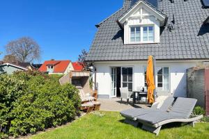 een wit huis met een parasol en een patio bij Strandhaus Zingst in Zingst