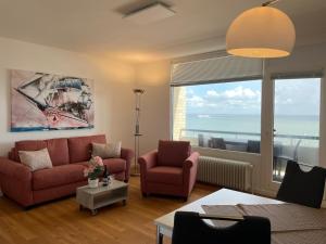 ein Wohnzimmer mit einem Sofa und Stühlen sowie einem großen Fenster in der Unterkunft Irma 28 in Wyk auf Föhr