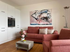 ein Wohnzimmer mit einem roten Sofa und einem Gemälde in der Unterkunft Irma 28 in Wyk auf Föhr