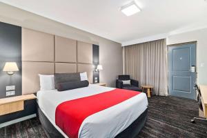 a hotel room with a large bed and a chair at Quality Hotel Parklake Shepparton in Shepparton