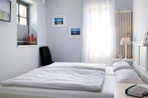 a white bedroom with a bed and a window at Wellenflüstern in Zingst