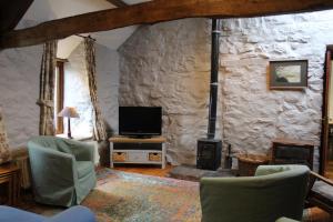 a living room with a fireplace and a tv at Ghyll Burn Cottage and Barn End Cottage in Alston
