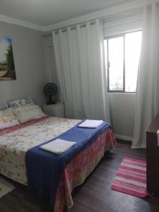 ein Schlafzimmer mit einem Bett und einem großen Fenster in der Unterkunft Quarto com banheiro privativo in Balneário Camboriú