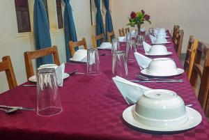 a long table with white plates and glasses on it at KLH REST HOUSE in Karatu