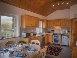 a kitchen with wooden cabinets and a table with dishes on it at Errislannan Stone Cottage in Errislannan