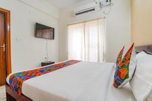 sypialnia z dużym białym łóżkiem z kolorowymi poduszkami w obiekcie FabHotel S V Homestay Tirupati w mieście Tirupati