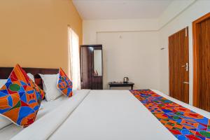 a bedroom with a bed with colorful pillows on it at FabHotel S V Homestay Tirupati in Tirupati