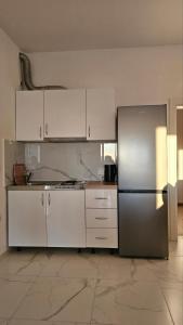 cocina con armarios blancos y nevera de acero inoxidable en Apartments Radoman, en Ulcinj
