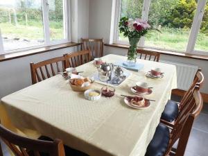 una mesa con un mantel blanco y un jarrón de flores en Hillside House, en Ballinaboy