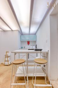 una cocina con 2 taburetes y un mostrador blanco en Authentic & cosy duplex home in charming Rabat By 360 Estates, en Rabat