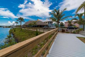 Merritt Island的住宿－Brand New House Boat Stunning Views and Resort Amenities，沿着水面的木板路,有房子和棕榈树