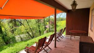 een patio met stoelen en een tafel en een oranje parasol bij Ruhige Oase in traumhafter Lage in Rabennest