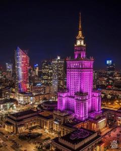 um edifício iluminado com uma torre de relógio à noite em 5Centrum Stanislawa Moniuszki10 Wi-fi 1Gb sek em Varsóvia