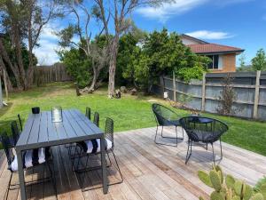 a wooden deck with a table and chairs on it at Coastal cottage, perfectly positioned in Tootgarook