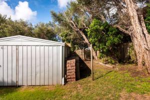 a white garage next to a tree and a fence at Coastal cottage, perfectly positioned in Tootgarook
