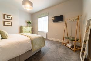 a bedroom with a bed and a tv on the wall at Queen's Cottage Barrowford in Barrowford
