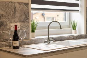 a kitchen sink with a bottle of wine and glasses at Queen's Cottage Barrowford in Barrowford
