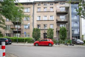 czerwony samochód zaparkowany przed budynkiem w obiekcie KrakowCharm No3 City Center w Krakowie