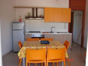 eine Küche mit einem Tisch mit orangefarbenen Stühlen und eine Küche mit einer Küche in der Unterkunft Casa Albertina in Castro di Lecce