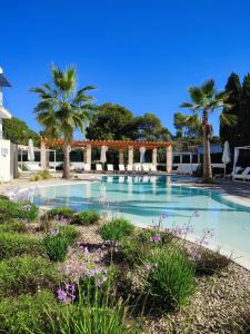 une grande piscine avec des palmiers et un ciel bleu dans l'établissement Sol i Vida Hotel - Adults Only, à Porto Cristo