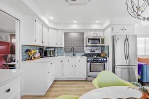una cocina con armarios blancos y electrodomésticos de acero inoxidable en Pura Vida - Cape Crossing Resort and Marina en Merritt Island