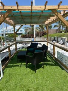 a patio with chairs and a wooden pergola at Seaside Escape A Cozy Houseboat in Merritt Island