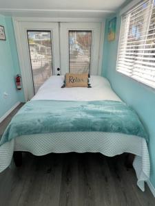 Cama grande en habitación con 2 ventanas en Seaside Escape A Cozy Houseboat, en Merritt Island