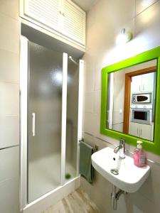 a bathroom with a sink and a green mirror at PRECIOSO Y PEQUEÑO LOFT CENTRO DE CONIL in Conil de la Frontera