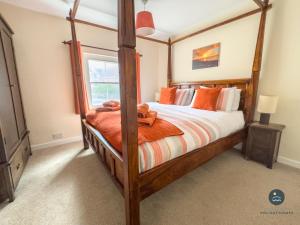 波特蘭的住宿－Dolphin Cottage Chesil Beach，一间卧室配有带橙色枕头的木床