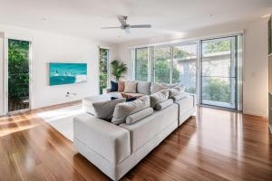 a white living room with a couch and some windows at Headlands Hideaway - Pet Friendly Home at Moffs in Caloundra