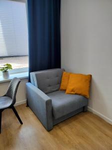 ein graues Sofa mit orangefarbenem Kissen im Zimmer in der Unterkunft STUDIO BLUE BIRD PIĘKNA 2 wejście na kod CENTRUM in Pabianice