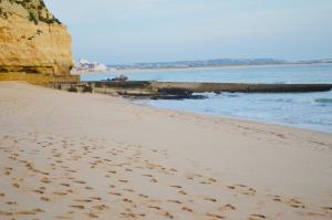 una spiaggia con impronte di piedi nella sabbia accanto all'acqua di Algarve dream seaview apartment w/pool near beach a Porches