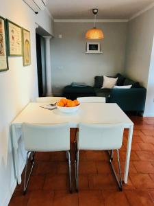 un tavolo bianco con sedie e una ciotola di arance di Algarve dream seaview apartment w/pool near beach a Porches